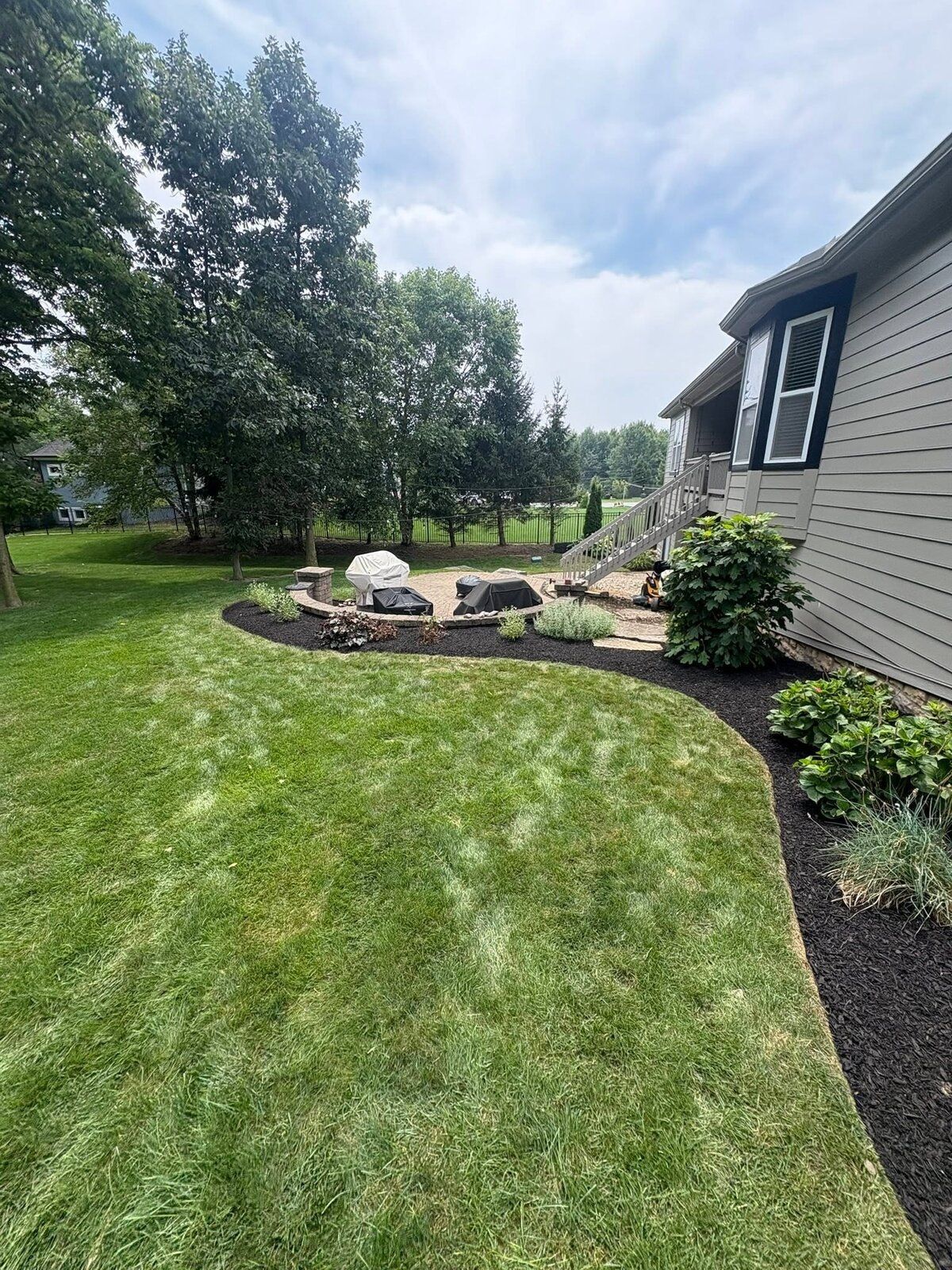 Backyard boulder feature set into a fresh mulch bed