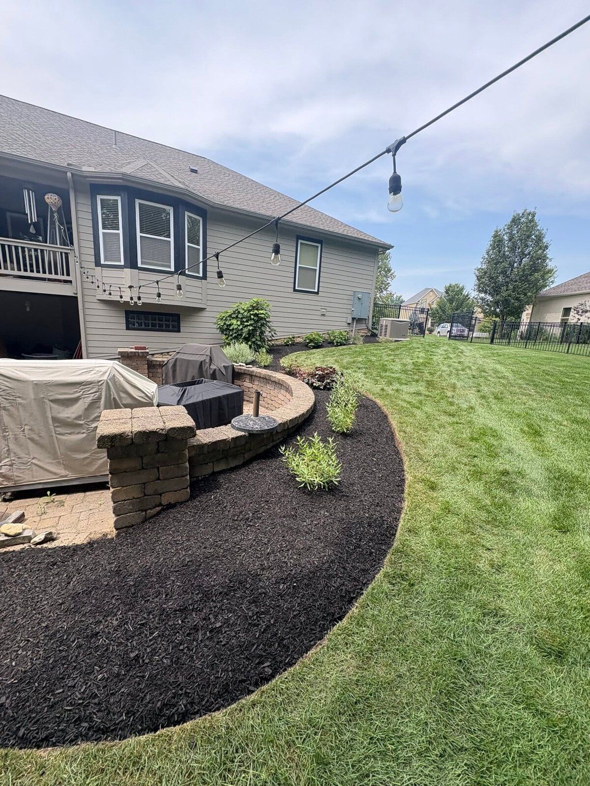 Stone fire-pit seating wall framed by a curved mulch bed