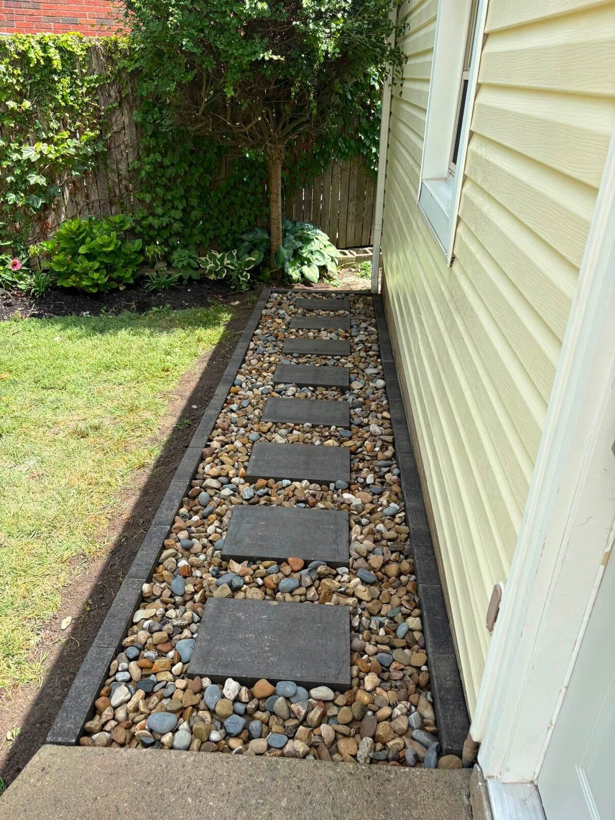Paver and river-rock path along the side of a home